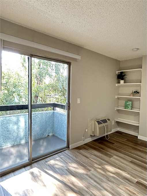 A room with a sliding glass door and a wood floor.