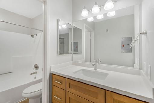 A white bathroom with a toilet, sink, and mirror.