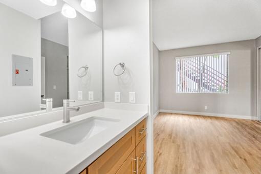 A bathroom with a white sink and wooden floors.