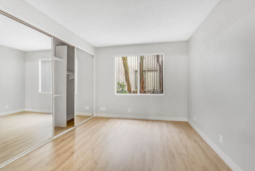 A room with a wooden floor and a large mirror on the wall.