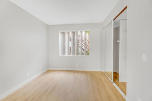 A room with wooden floors and a window with blinds.