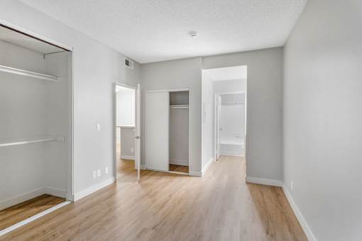 A white room with wood floors and a closet with a sliding door.