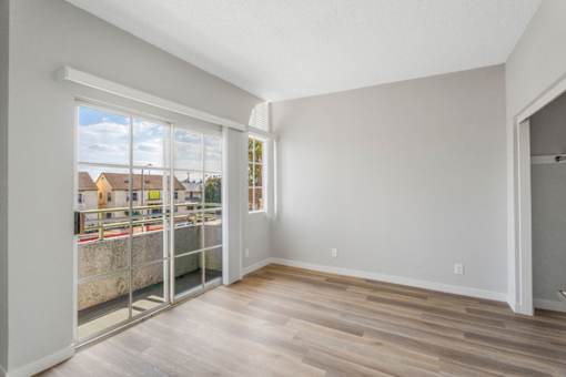 A room with a sliding glass door leading to a balcony.