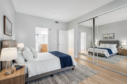 A bedroom with a large bed and a mirror on the wall.