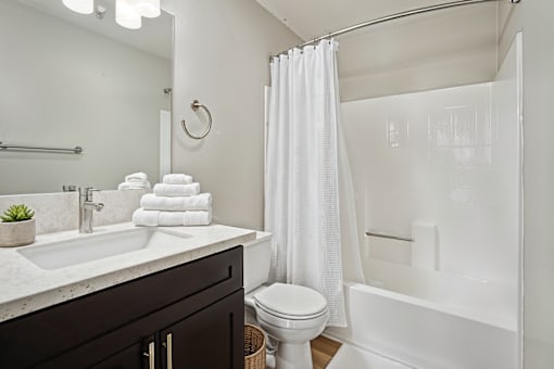 A white bathroom with a toilet, sink, and shower.