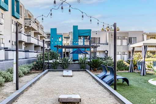 a courtyard with a pool and chairs and a blue building