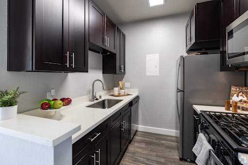 a kitchen with black cabinets and stainless steel appliances and a white counter top