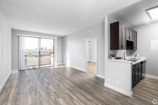an open living room and kitchen with a sliding glass door to a balcony