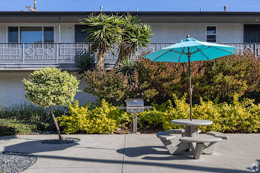 A blue umbrella is on a table in the middle of a courtyard.