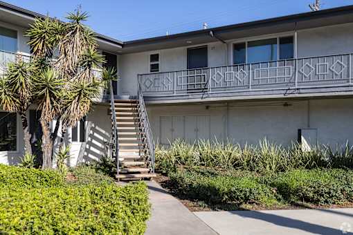 A white building with a balcony and stairs leading to it.