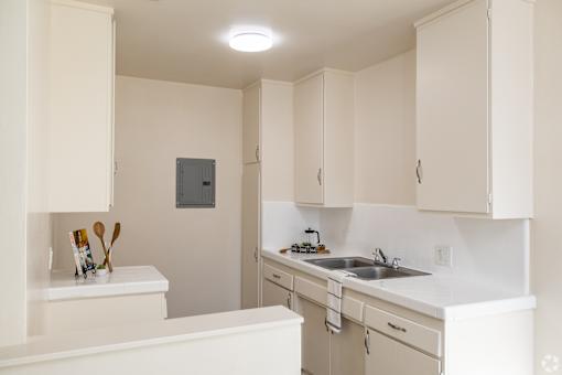 A small kitchen with white cabinets and a white counter top.