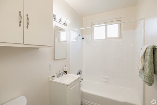 A white bathroom with a towel hanging on the rack.