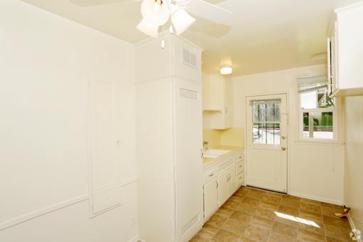A kitchen with white cabinets and a ceiling fan.