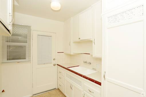 A white kitchen with a red counter.