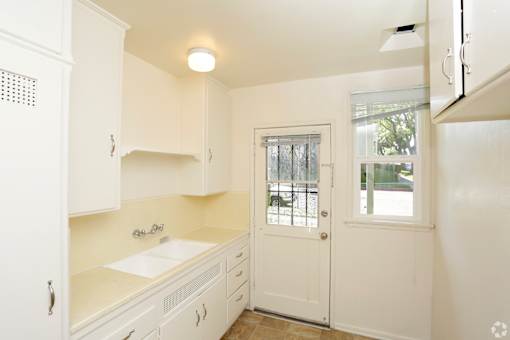 A small kitchen with white cabinets and a white door.