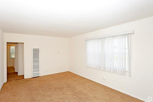 A room with a window covered by white blinds.