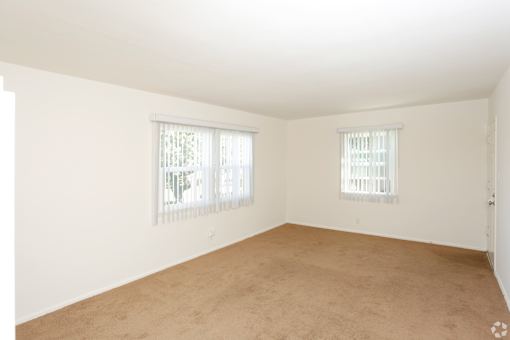 A large empty room with two windows.