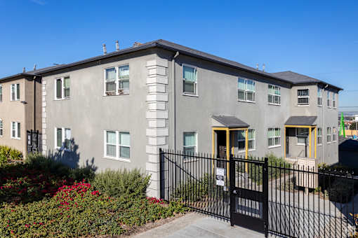 A grey building with a black fence and gate in front.