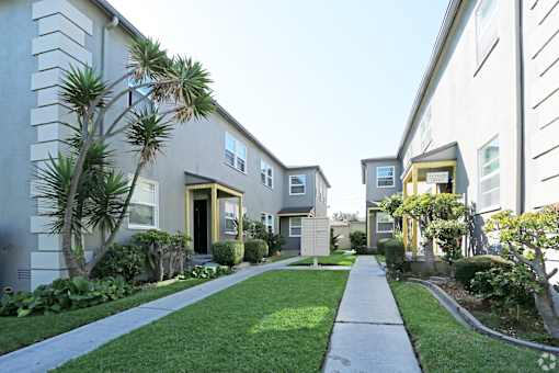 A row of houses with a sidewalk in front.