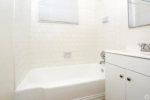 A white bathroom with a tub, sink, and mirror.