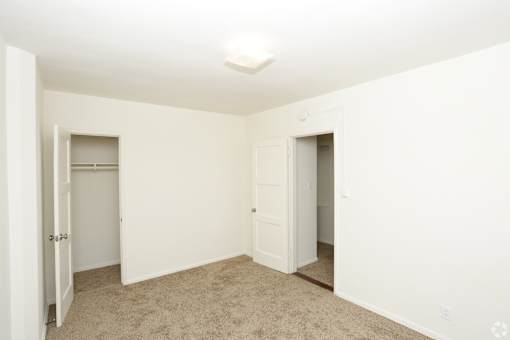 A white room with carpeted floor and two doors.