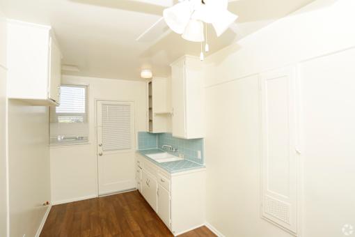 A kitchen with white cabinets and a blue backsplash.
