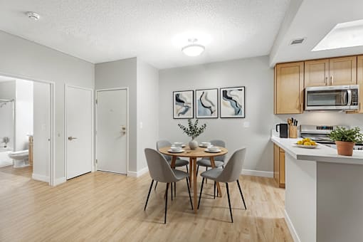 A kitchen with a dining table and chairs.