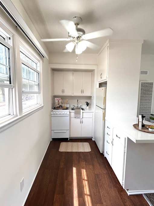A kitchen with white cabinets and a fan on the ceiling.