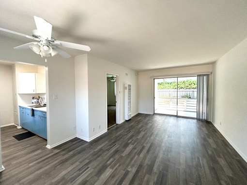 A room with a ceiling fan and sliding glass doors.