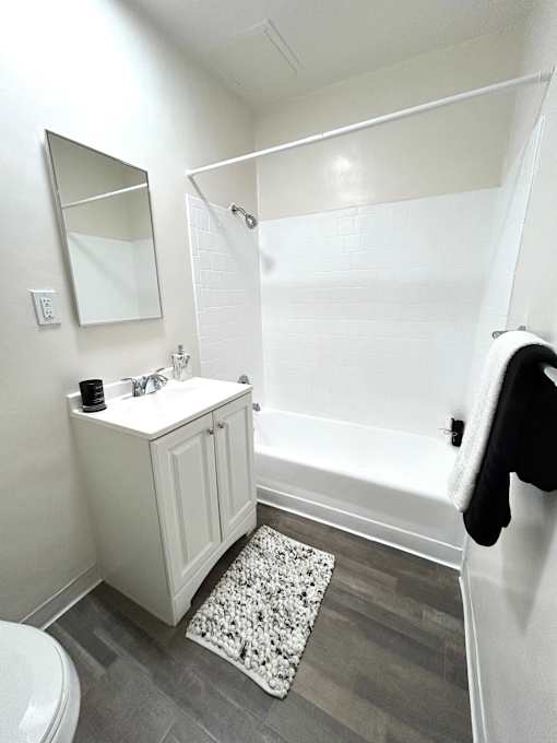 A white bathroom with a toilet, sink, and mirror.