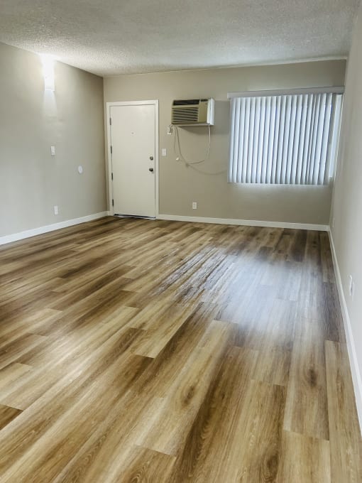 an empty living room with wood flooring and a window