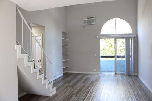 A room with a staircase and a sliding glass door.