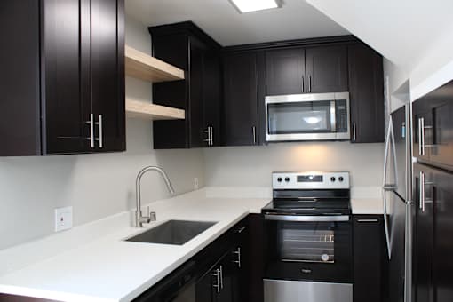 A kitchen with black cabinets and stainless steel appliances.