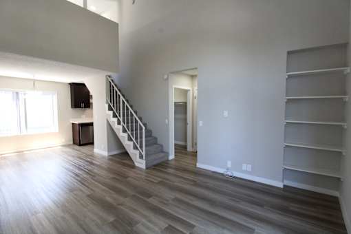 A room with a staircase and a flat screen TV mounted on the wall.