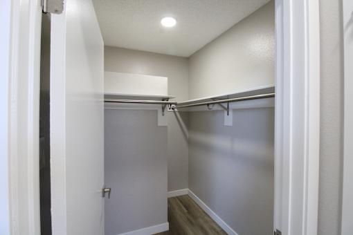 A white hallway with a grey door and a light on the ceiling.