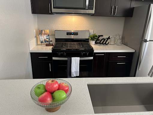 a kitchen with black cabinets and a bowl of apples