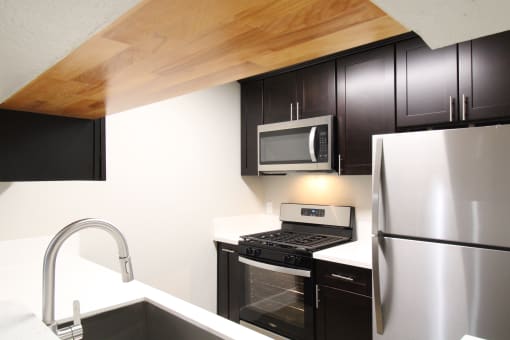 a kitchen with stainless steel appliances and Expresso Colored cabinets