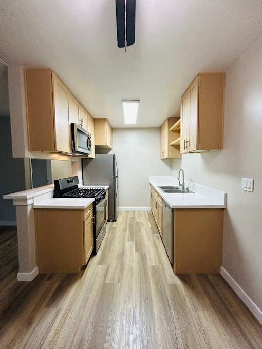 A kitchen with wooden cabinets and a white counter.