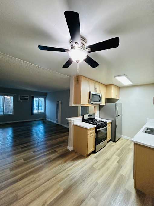 A kitchen with a fan and wooden floors.