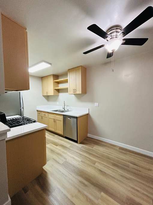 A kitchen with a fan and wooden floors.