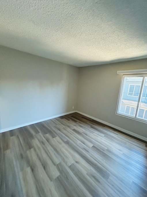 A room with a window and wooden flooring.