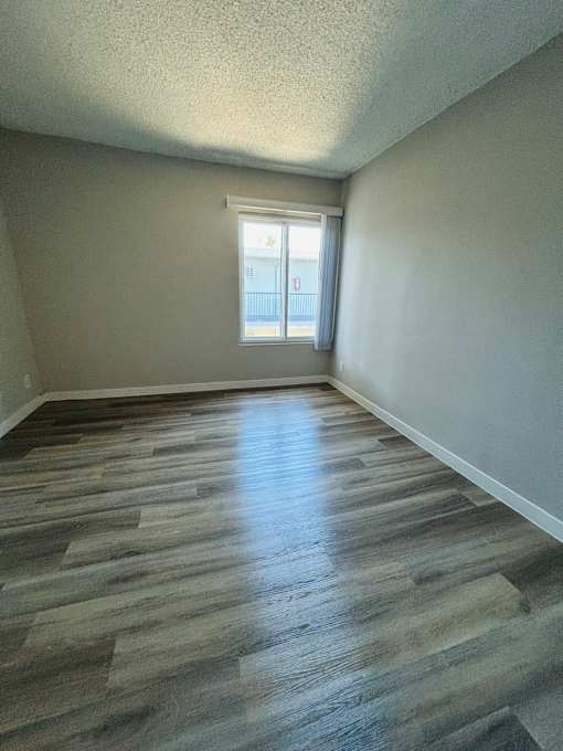 A room with wooden flooring and a window letting in light.