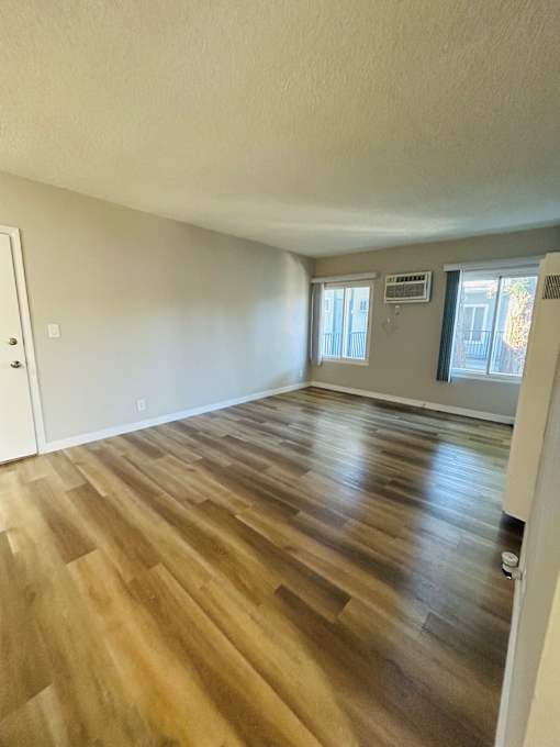 A room with wooden flooring and a door on the left side.