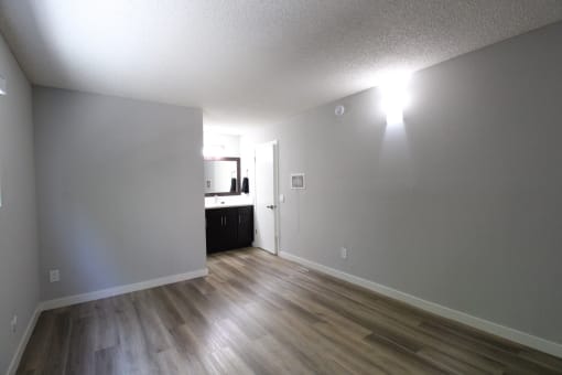 an empty living room with wood floors and a kitchen