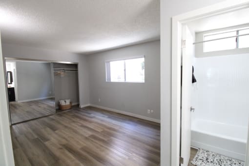 an empty living room and a bathroom with a shower and a bath tub
