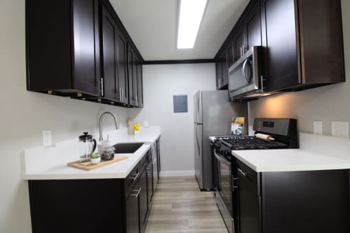 a kitchen with black cabinets and white counter tops and a stainless steel refrigerator