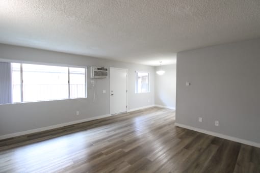 an empty living room with wood floors and a window