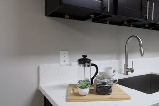a kitchen sink with a coffee maker on a cutting board