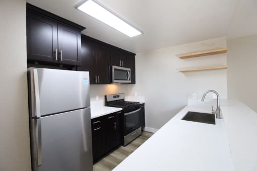 an apartment kitchen with stainless steel appliances and black and white counter tops
