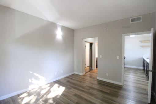 an empty living room with wood floors and white walls and closets